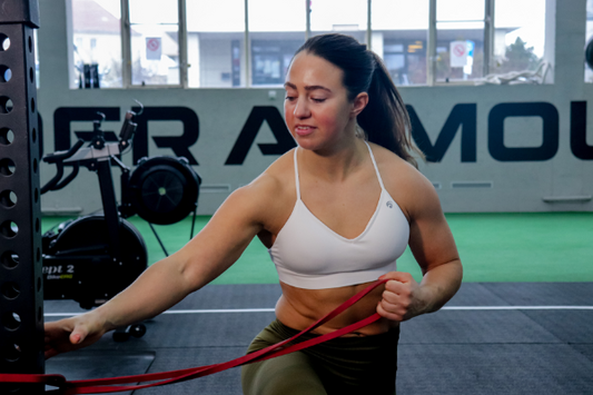 Frau in weißem Sport-BH trainiert mit Bändern